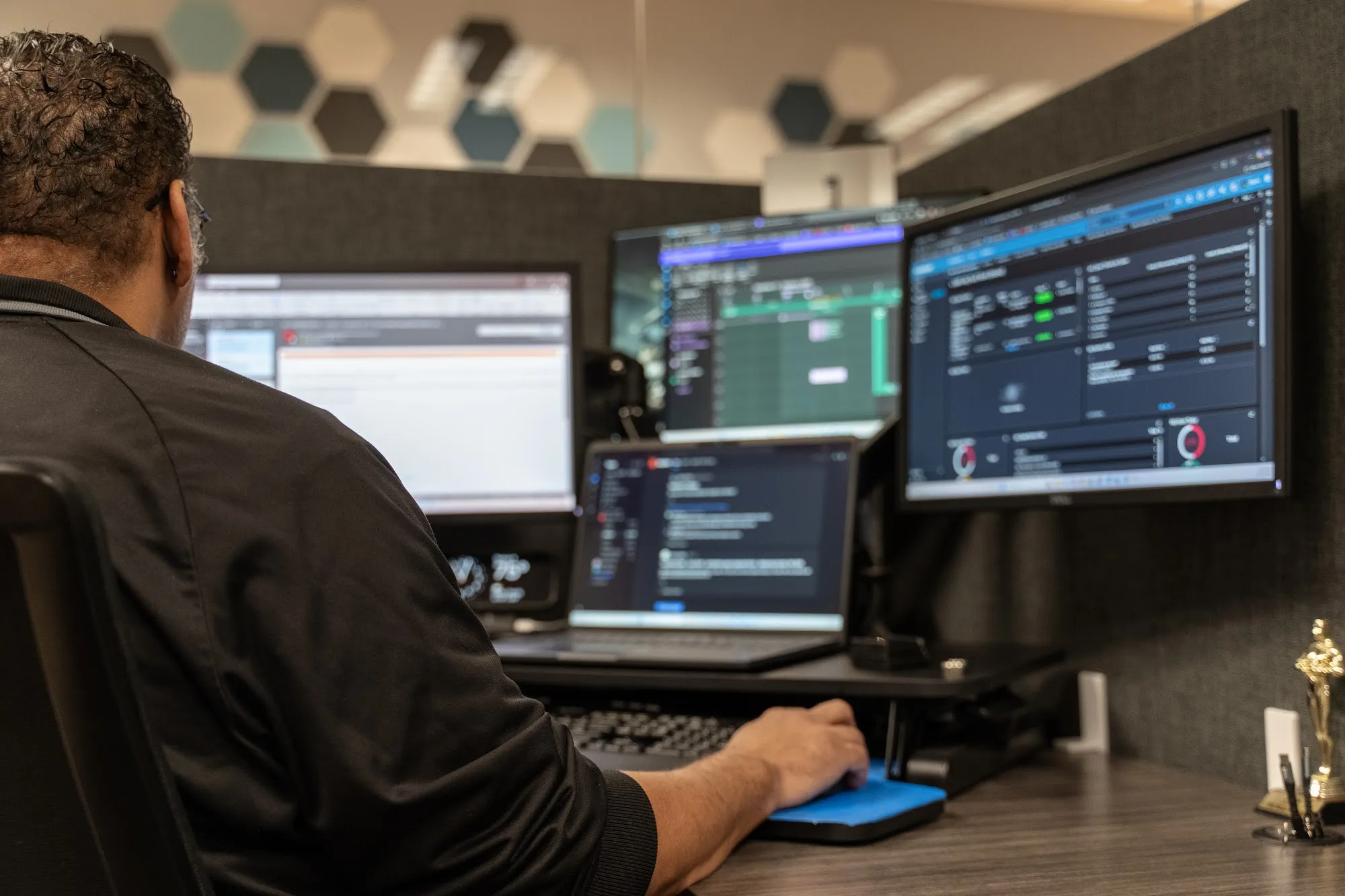 A Marcus Networking technician working a ticket at a help desk station with live monitoring dashboards
